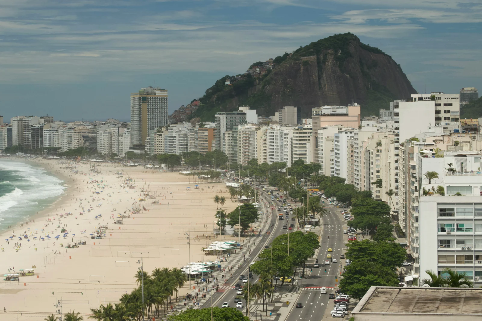 Copacabana vista entre edificios, con la playa y la avenida extendiéndose hasta un promontorio verde