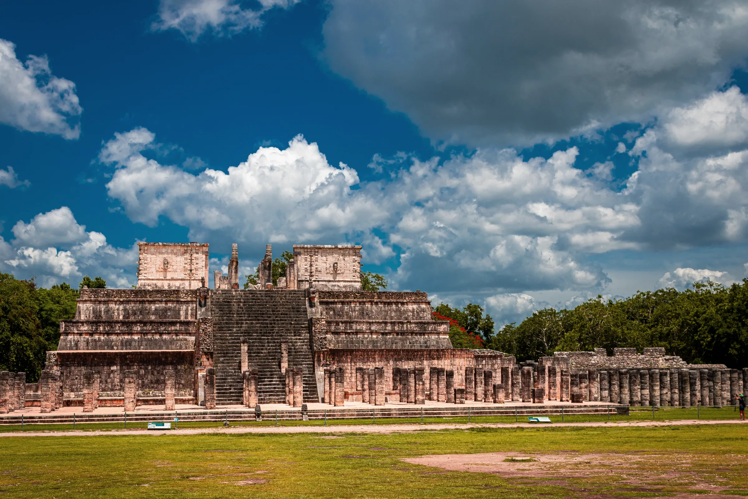 O Templo dos Guerreiros de Chichén Itzá, em degraus, com a escadaria e fileiras de colunas de pedra, e gramado à frente