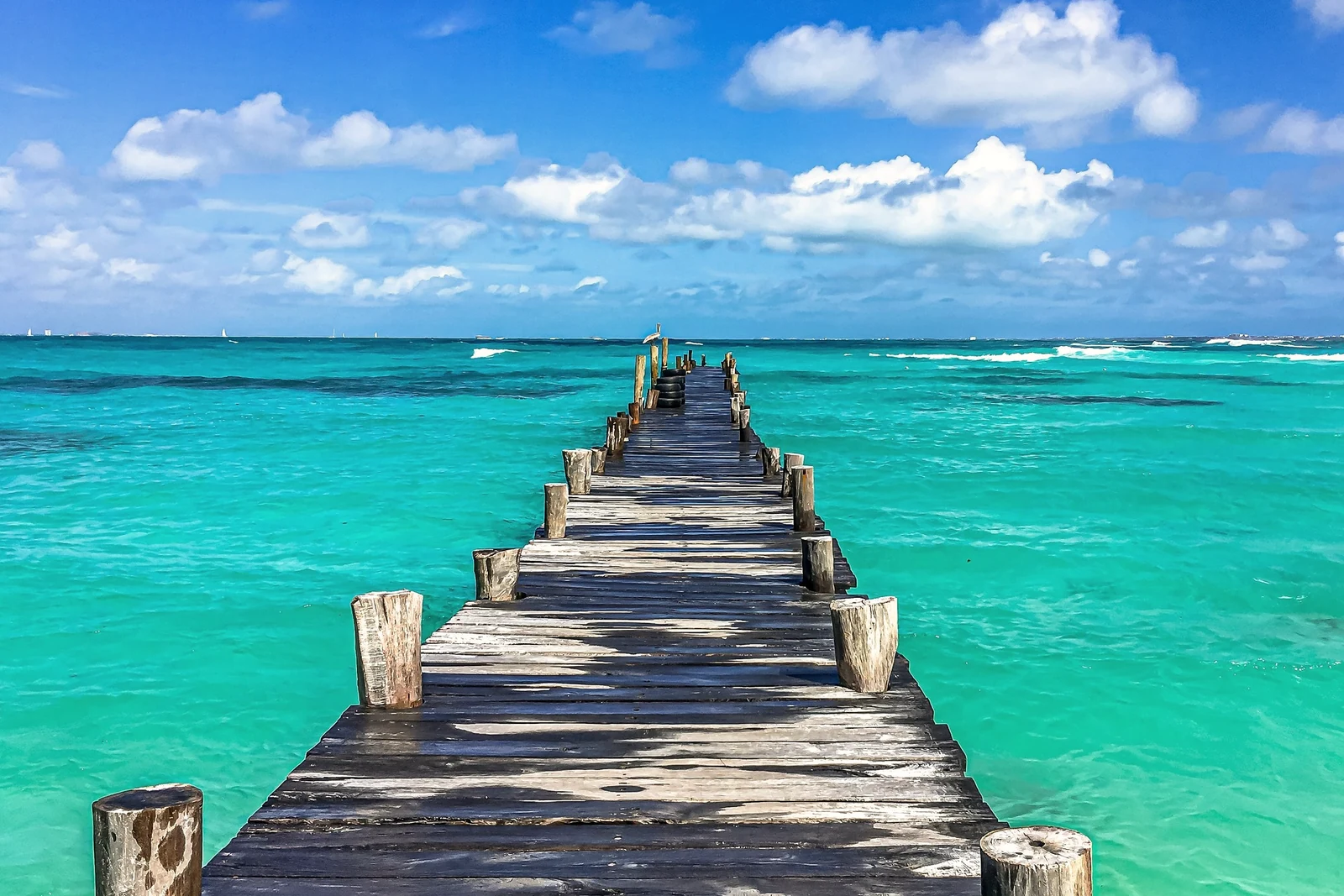 A weathered wooden pier reaching into shallow turquoise water