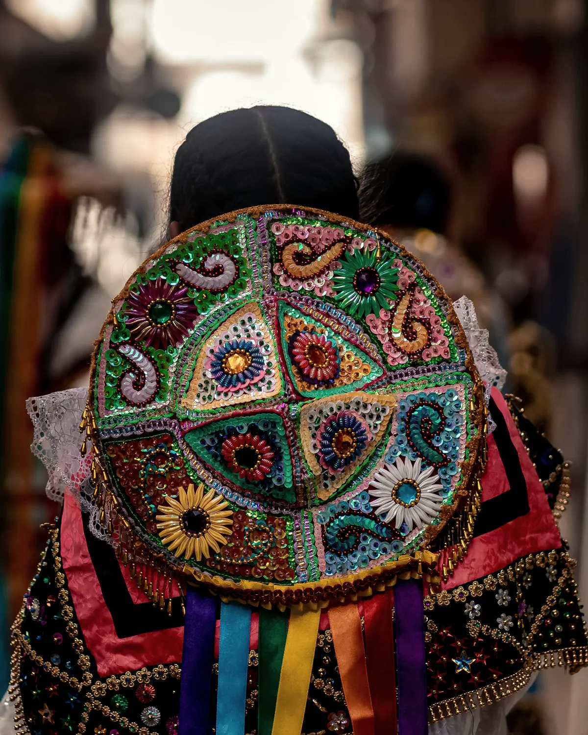 A hat sewn over with sequins and ribbon, seen from behind