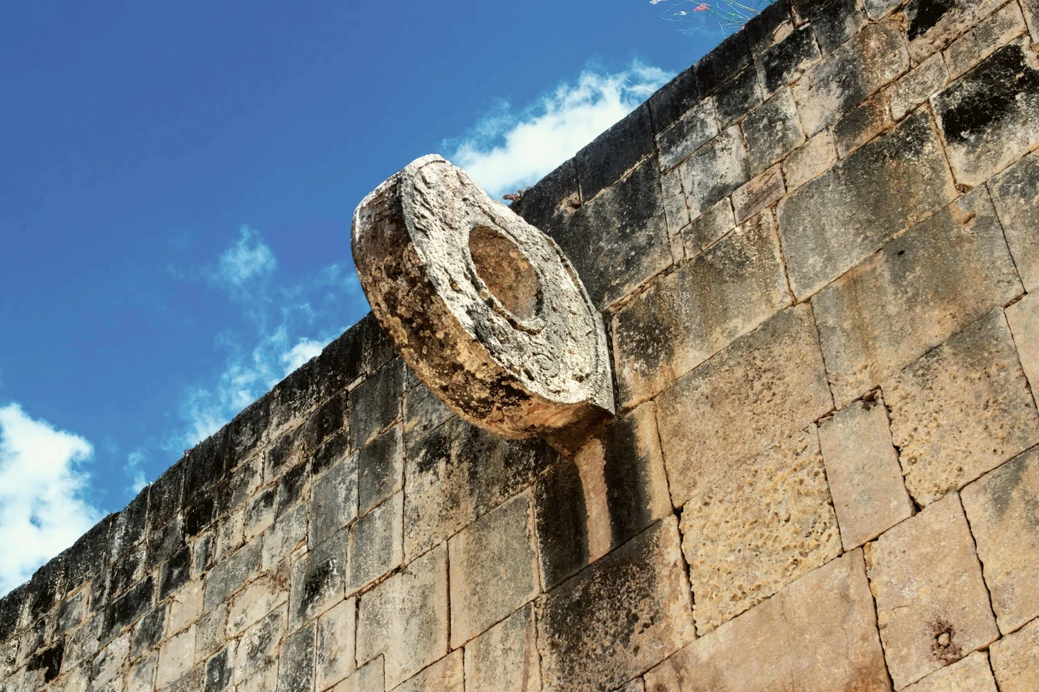 The carved stone ring set high in the wall of the ball court at Chichén Itzá, against a blue sky