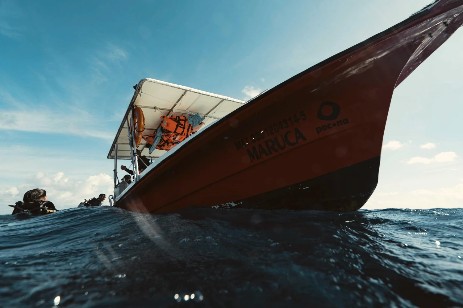A wooden dive boat on dark blue water, seen from the surface of the sea