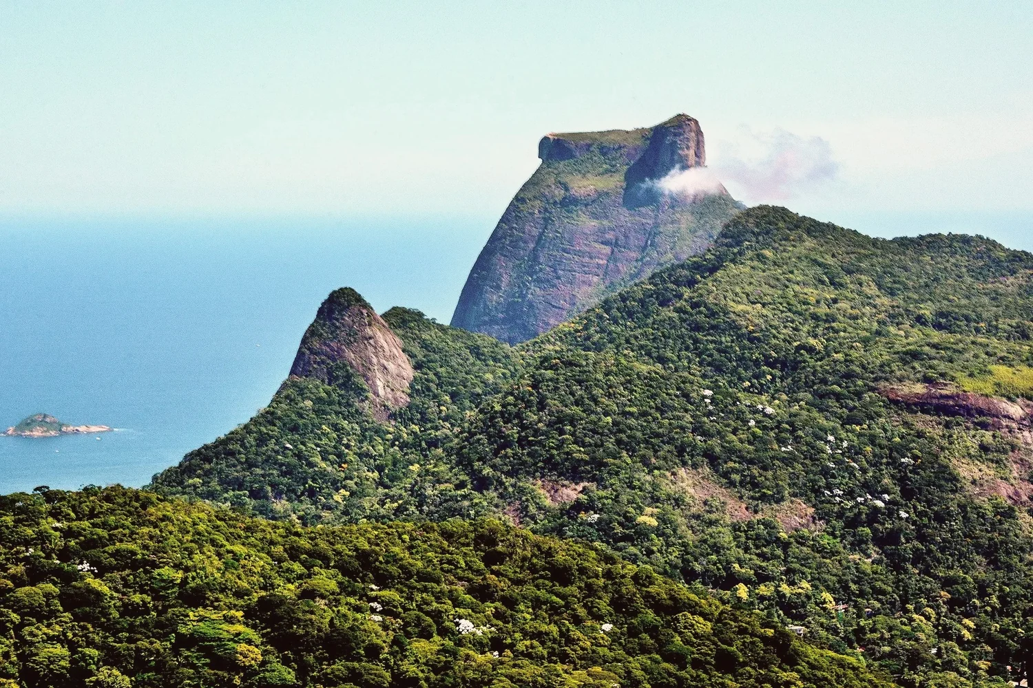 Pedra da Gávea rising above the green slopes of the Tijuca forest, with the sea and a small island beyond
