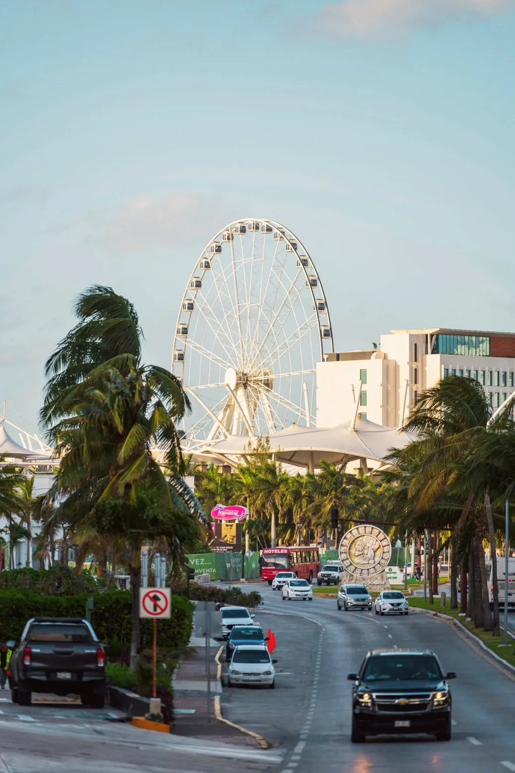 A red Hoteles bus on Kukulcán Boulevard, a Ferris wheel behind
