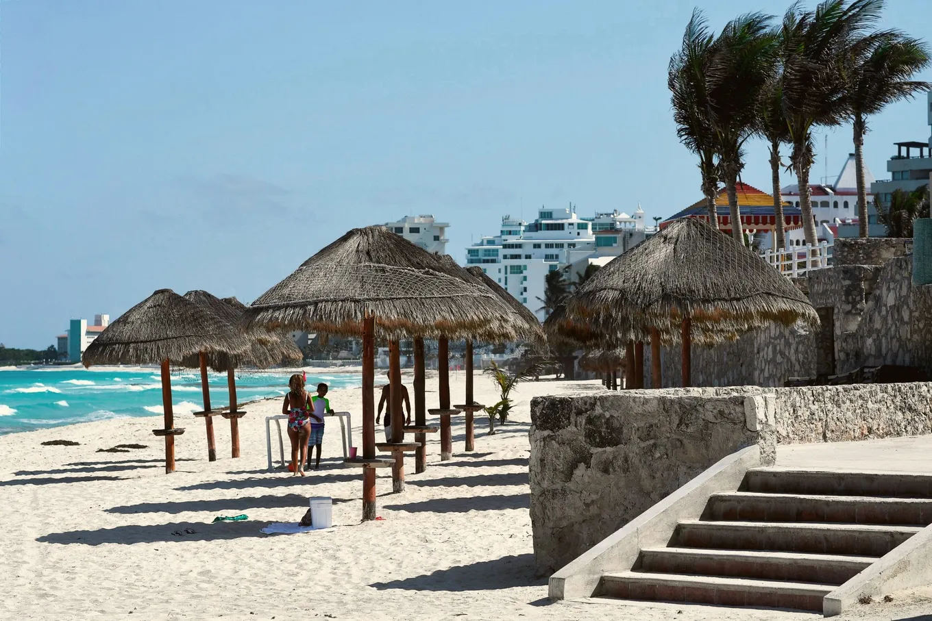 Palapas and stone steps down to white sand