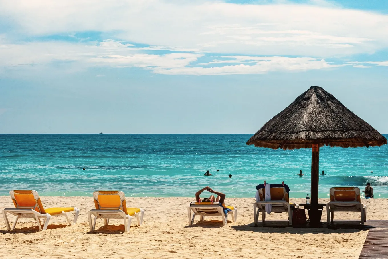 Yellow loungers under a palapa, the Caribbean behind