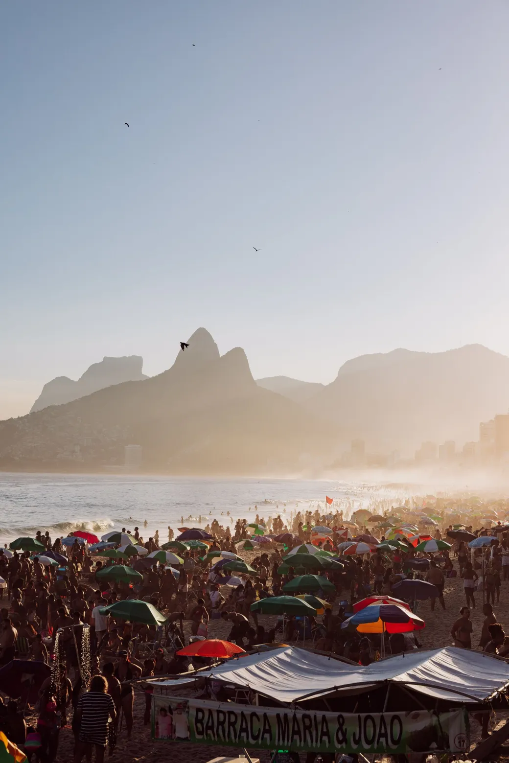 Umbrellas and crowds on the sand, Dois Irmãos in the haze