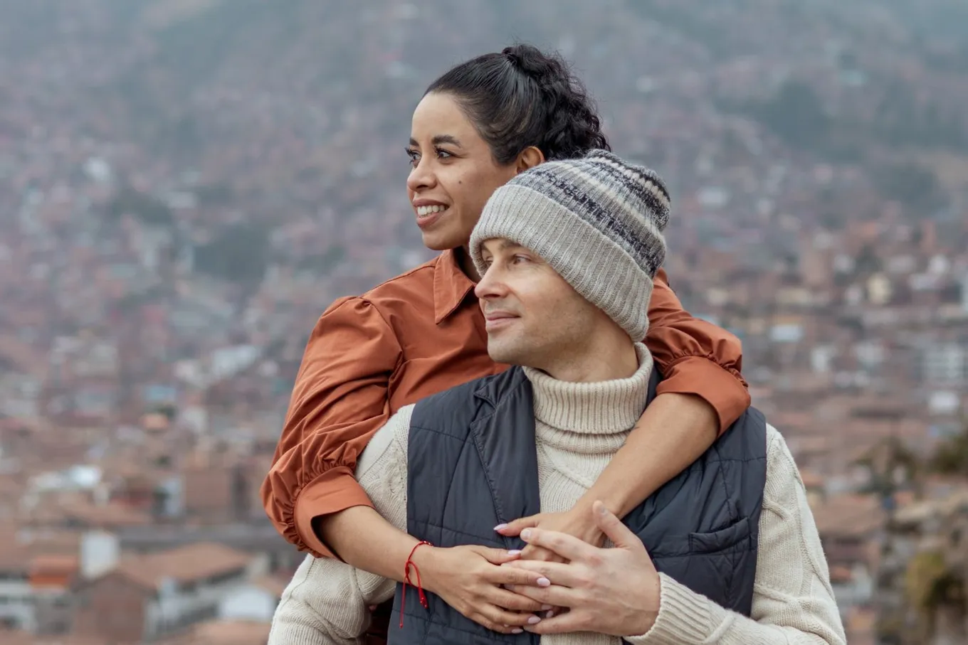 Melissa embracing Aleksejs from behind, with the tiled roofs of Cusco below them
