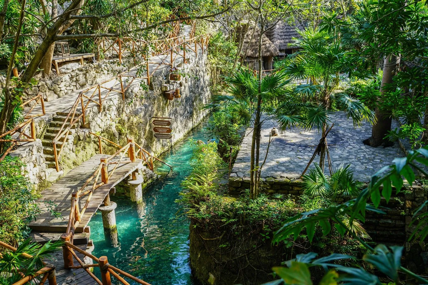 A clear canal under a wooden bridge at Xcaret