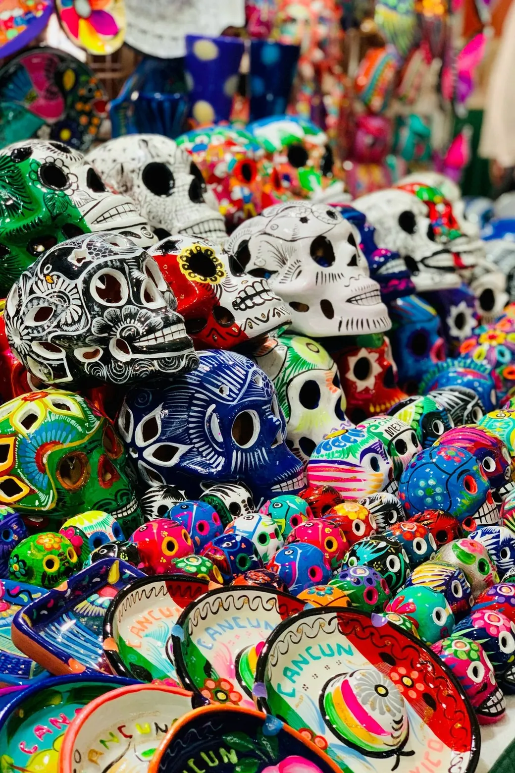Painted skulls and bowls lettered Cancún, stacked for sale