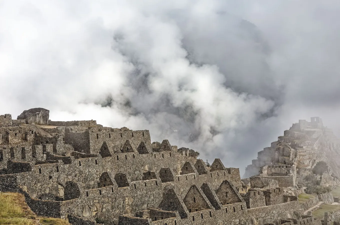 Cloud rising behind the stone houses of Machu Picchu