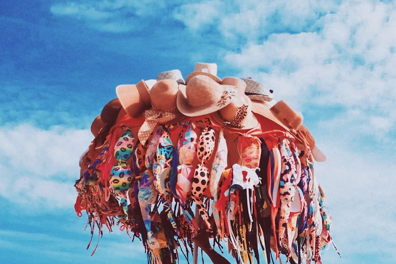 A beach vendor's umbrella of hats and bikinis