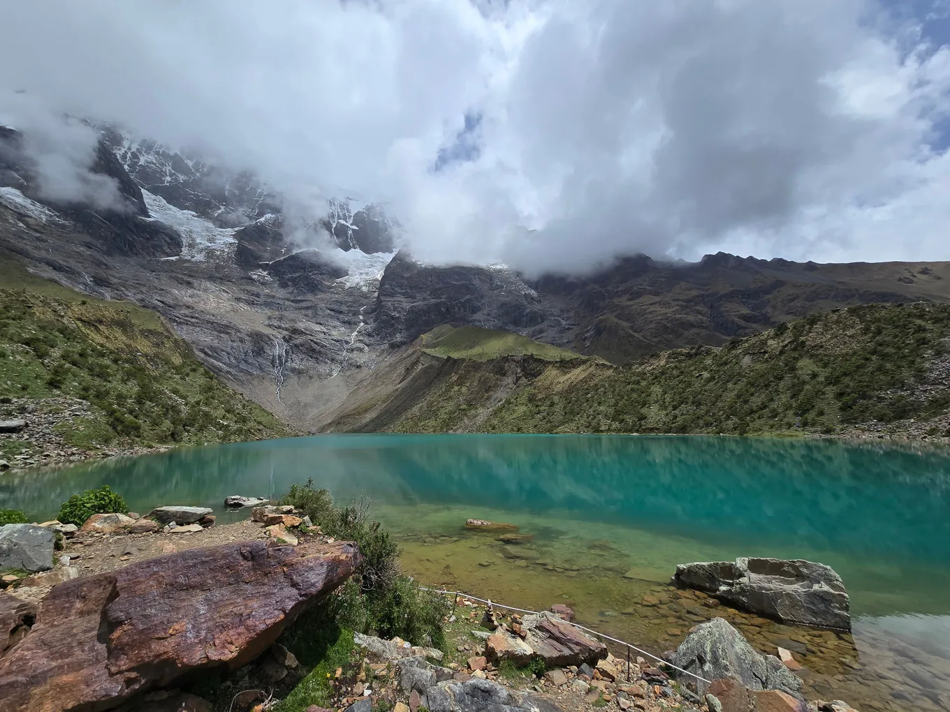 Turquoise water of Humantay Lake under cloud, at the foot of the glacier