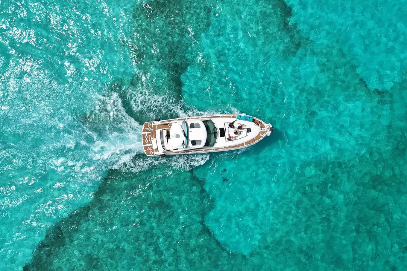 A boat crossing turquoise water over a dark reef