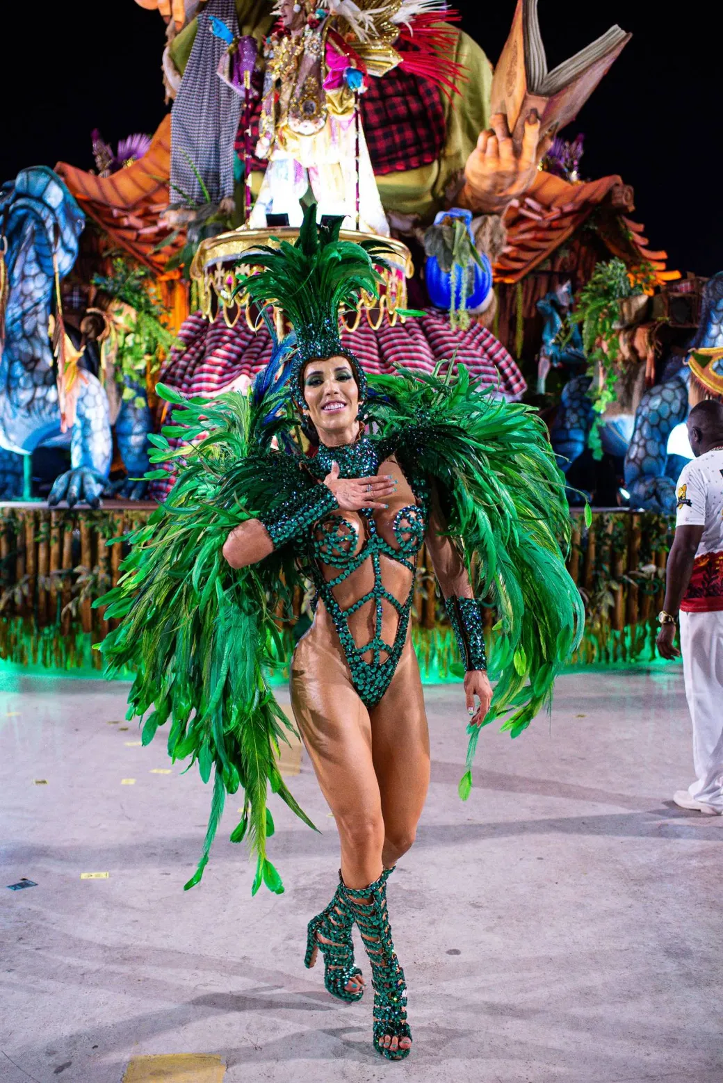 A dancer in green feathers in front of a float