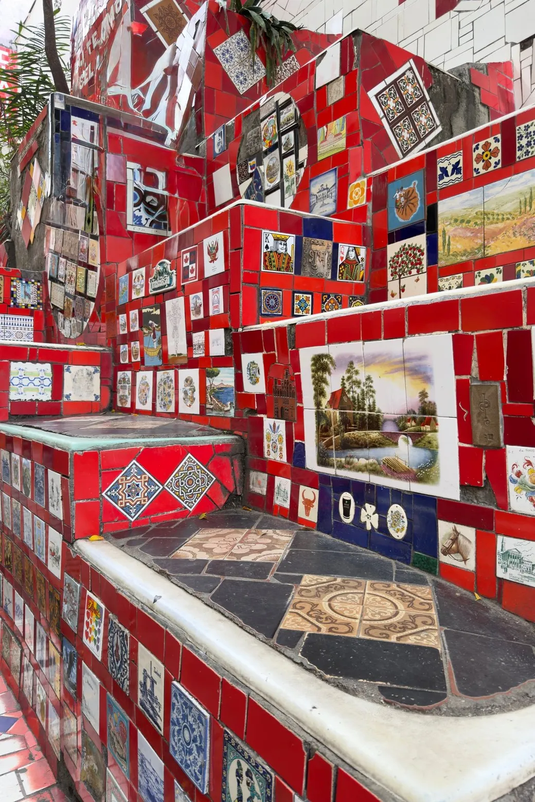 Painted tiles on a red wall, a landscape set among them