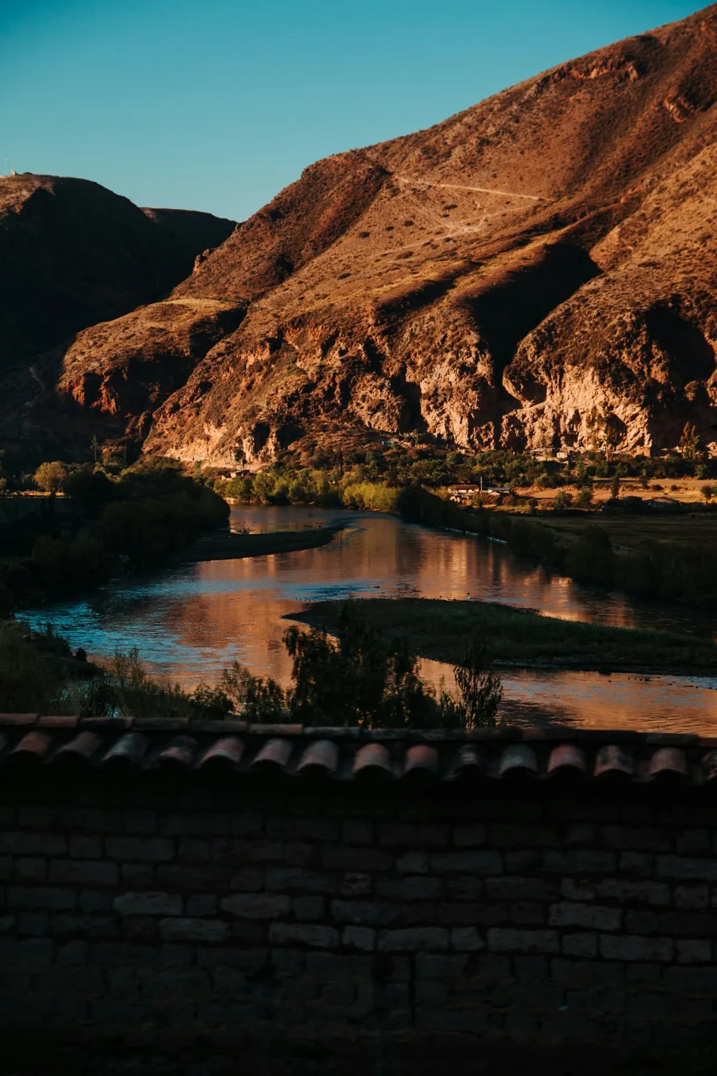 A river bend below dry slopes, in late sun