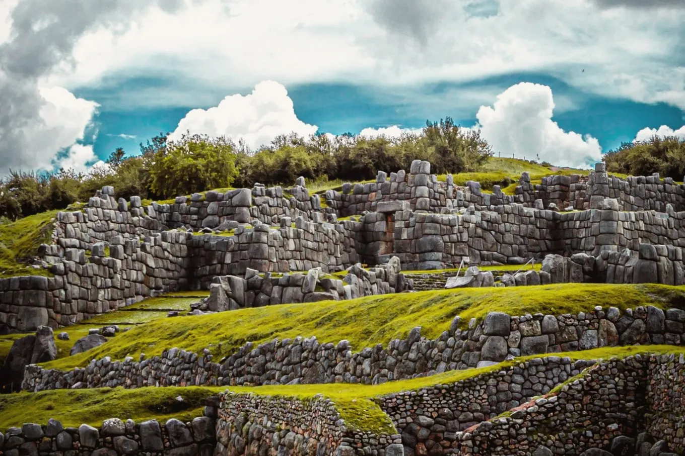 Terraced Inca walls on green slopes under a heavy sky