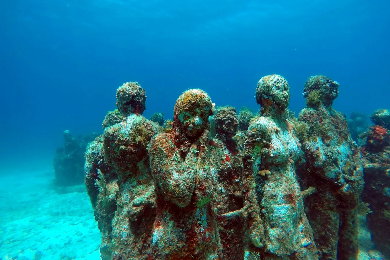 Figures of the underwater museum, grown over with coral