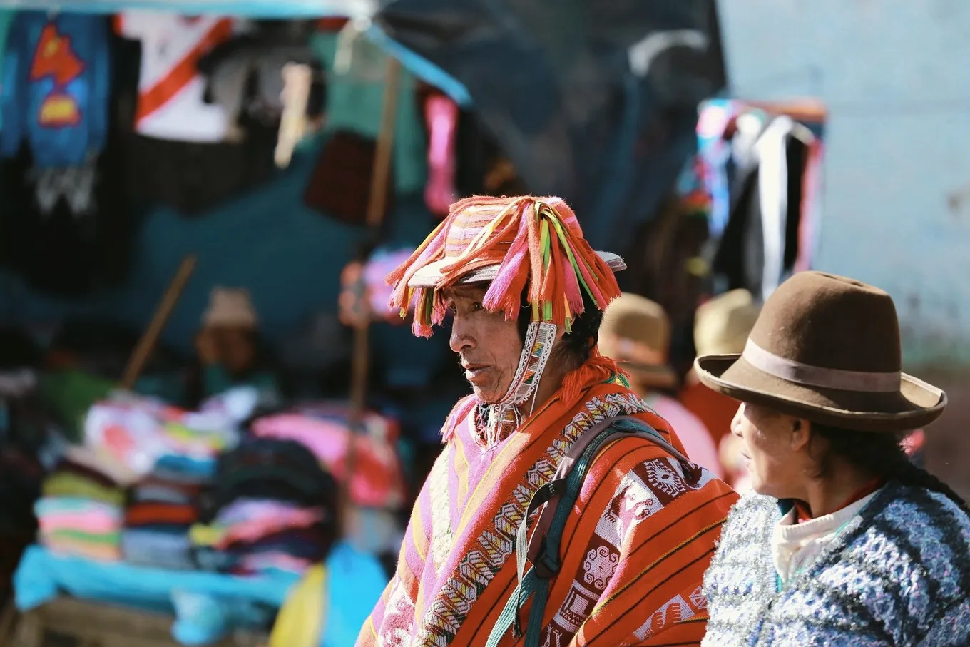 Two people at a market, one under a fringed hat