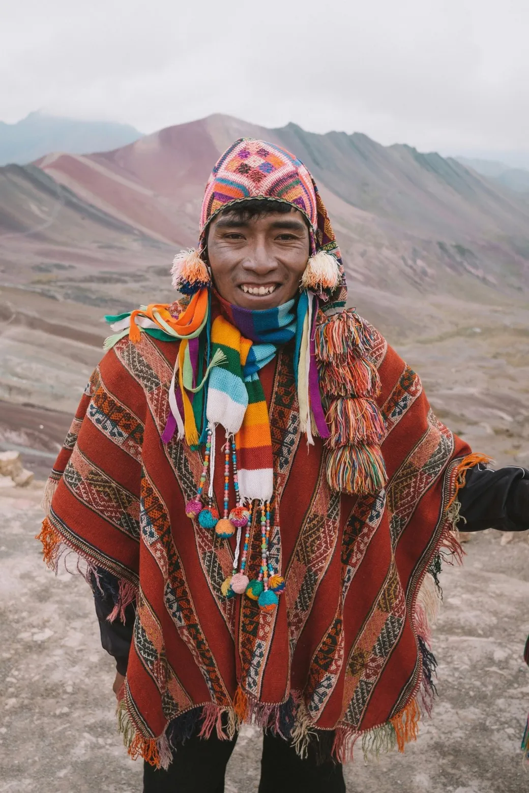 A man in a red poncho, striped slopes behind him