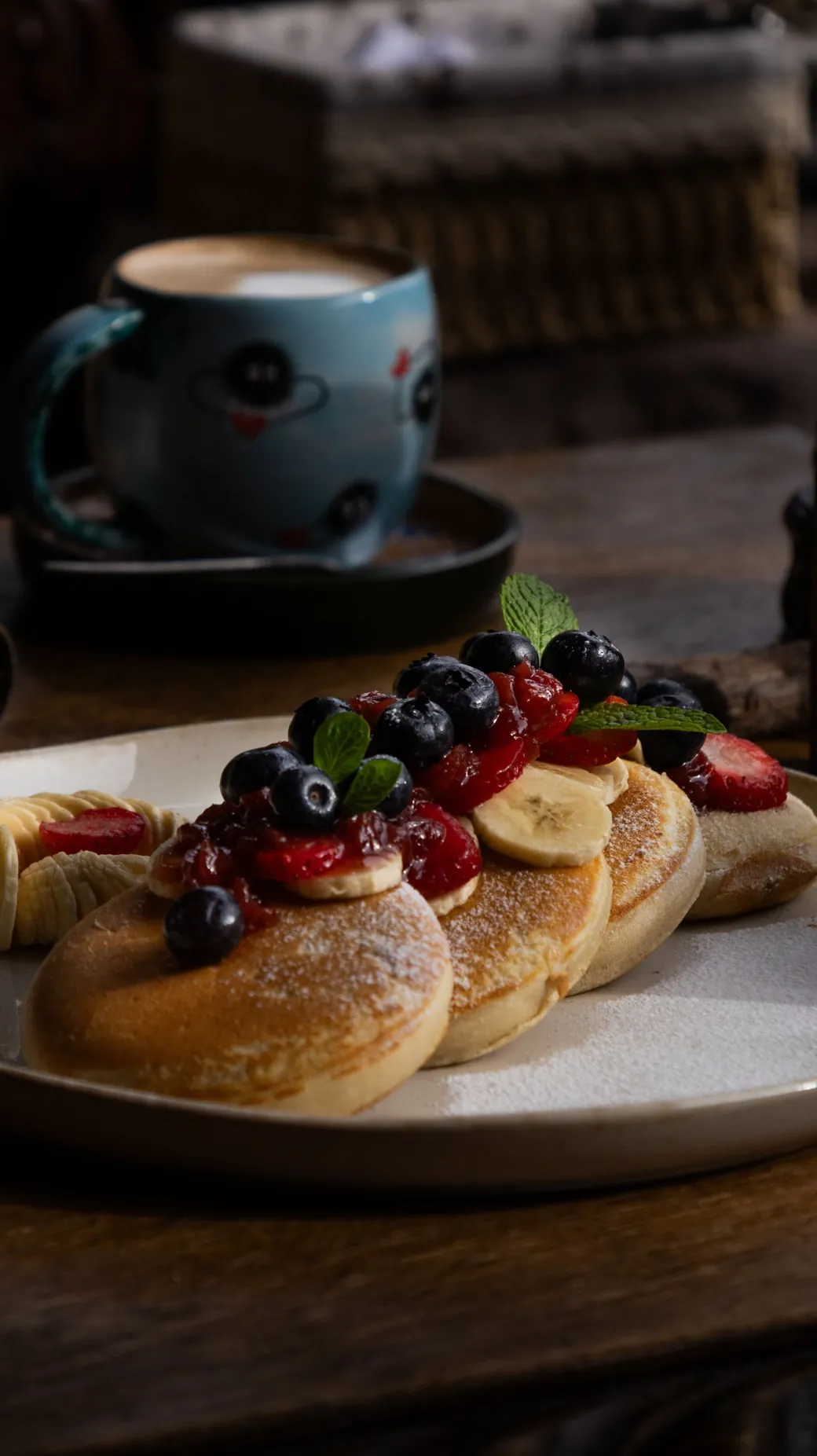 Pancakes with berries, a cup of coffee behind them