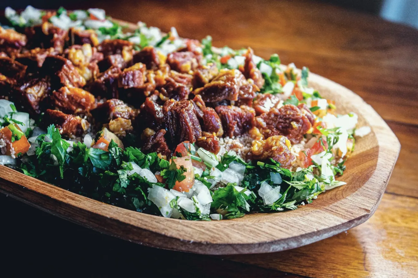 Grilled meat over chopped tomato, onion, and greens