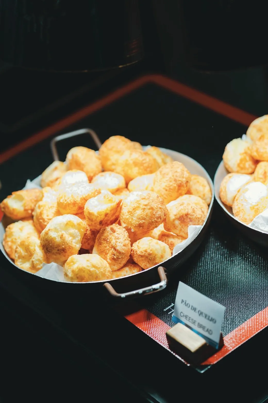 Small rolls of cheese bread, piled in a metal pan