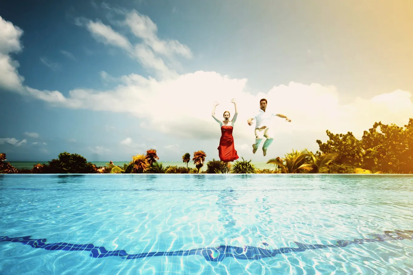 A couple jumping into a pool