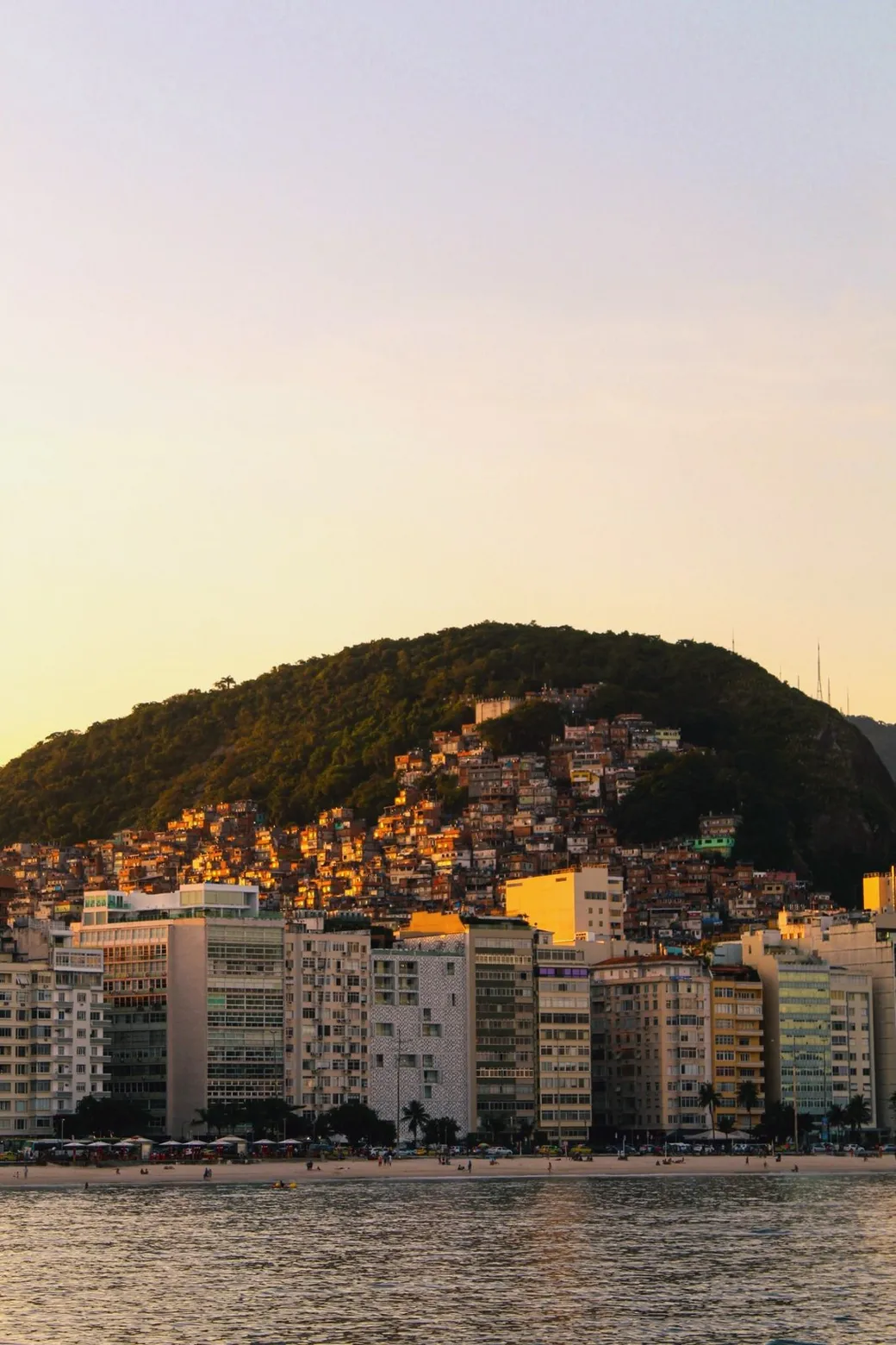 Apartment blocks along the sand, a green hill behind